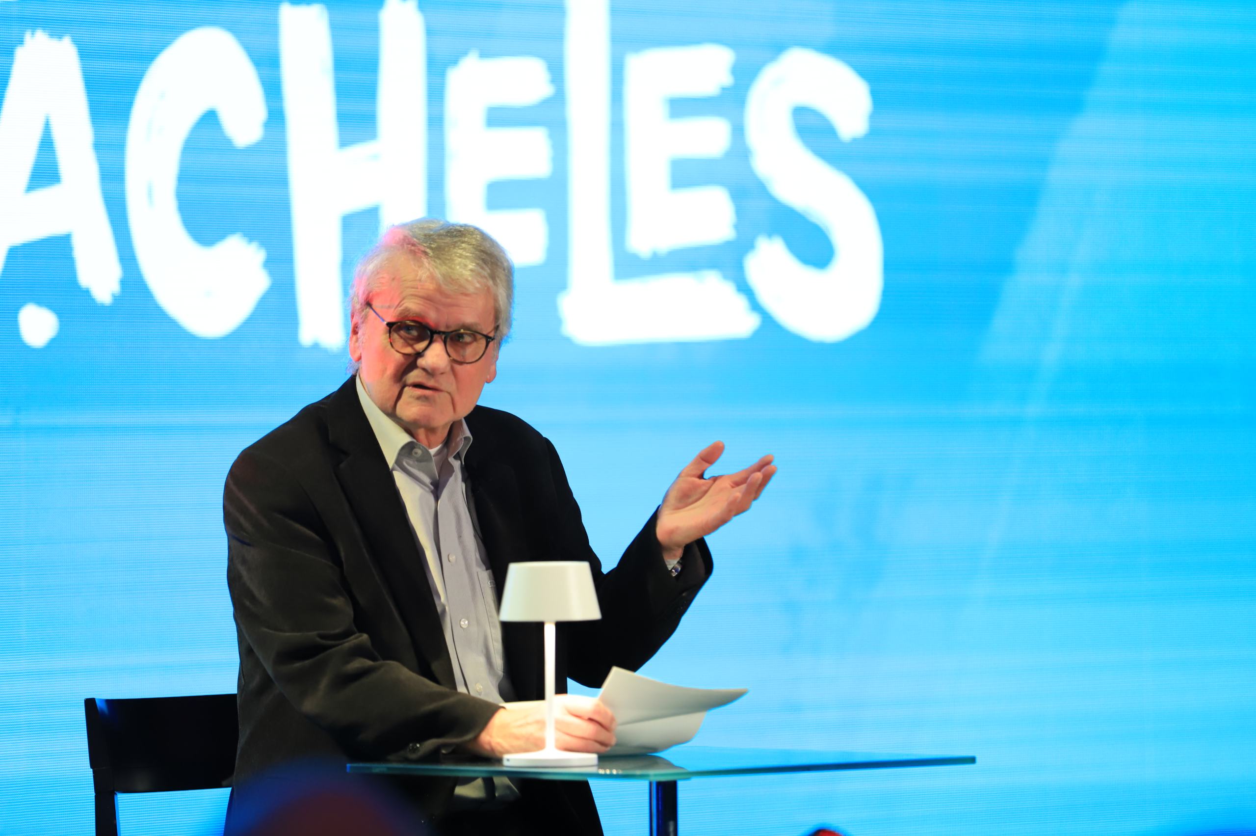 Ein Mann in schwarzem Anzug vor einer Leinwand