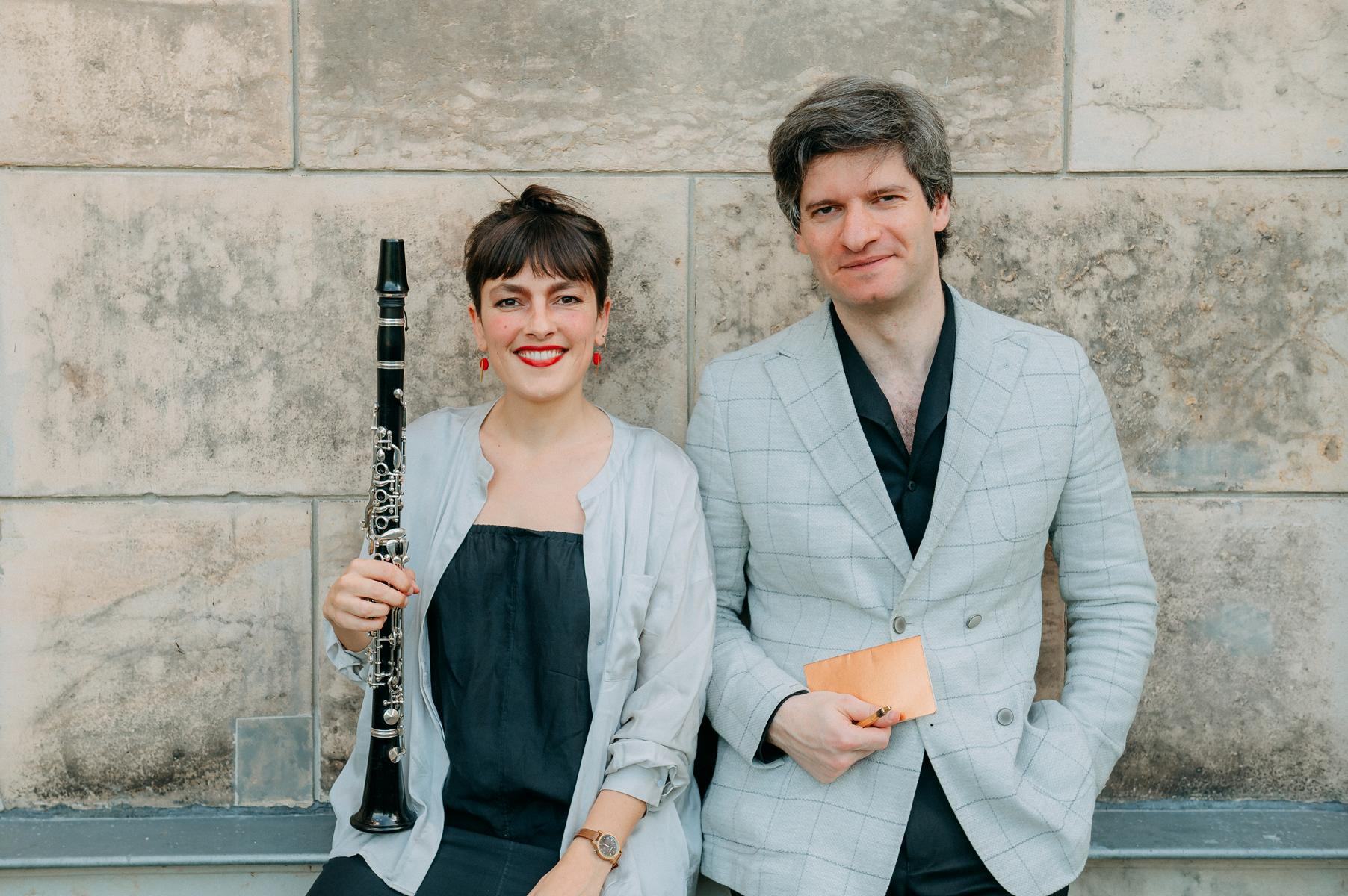 Die Musikerin Tatjana Davis und der Schrifsteller Alexander Estis posieren vor einer Wand.