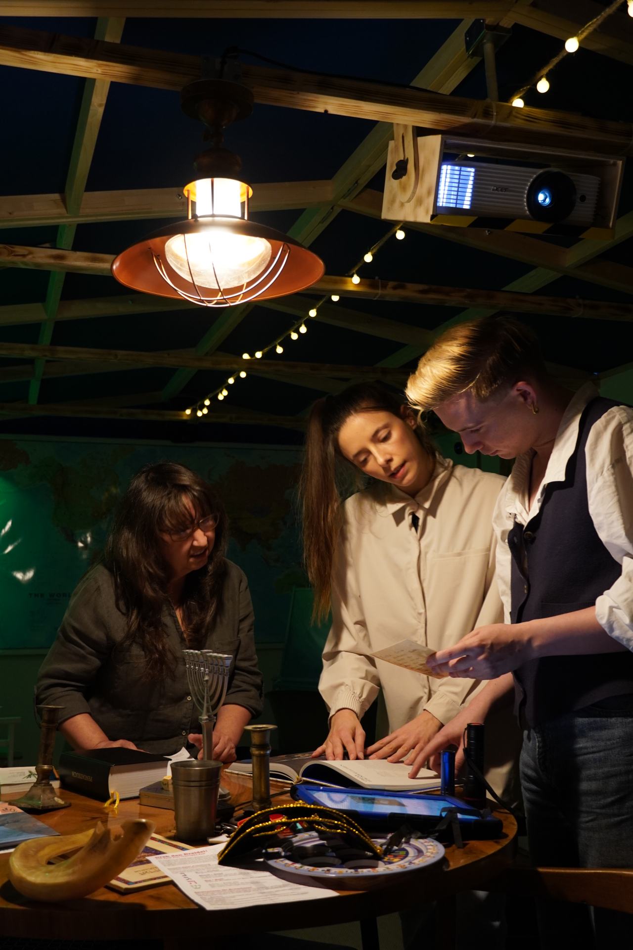 Drei Personen stehen im Escape-Room und schauen sich das Material an.