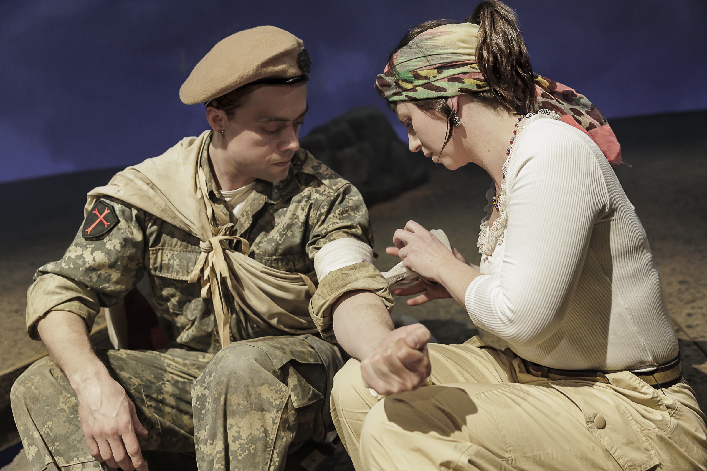 Eine Frau in Freizeitkleidung verbindet den den Arm eines Mannes in Militäruniform und Baskenmütze.