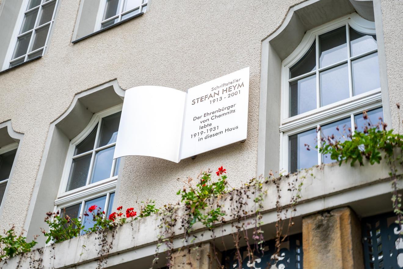 Ein helles Haus, zwischen zwei Fenstern eine Gedenktafel in Form eines Buchs in Erinnerung an Stefan Heym