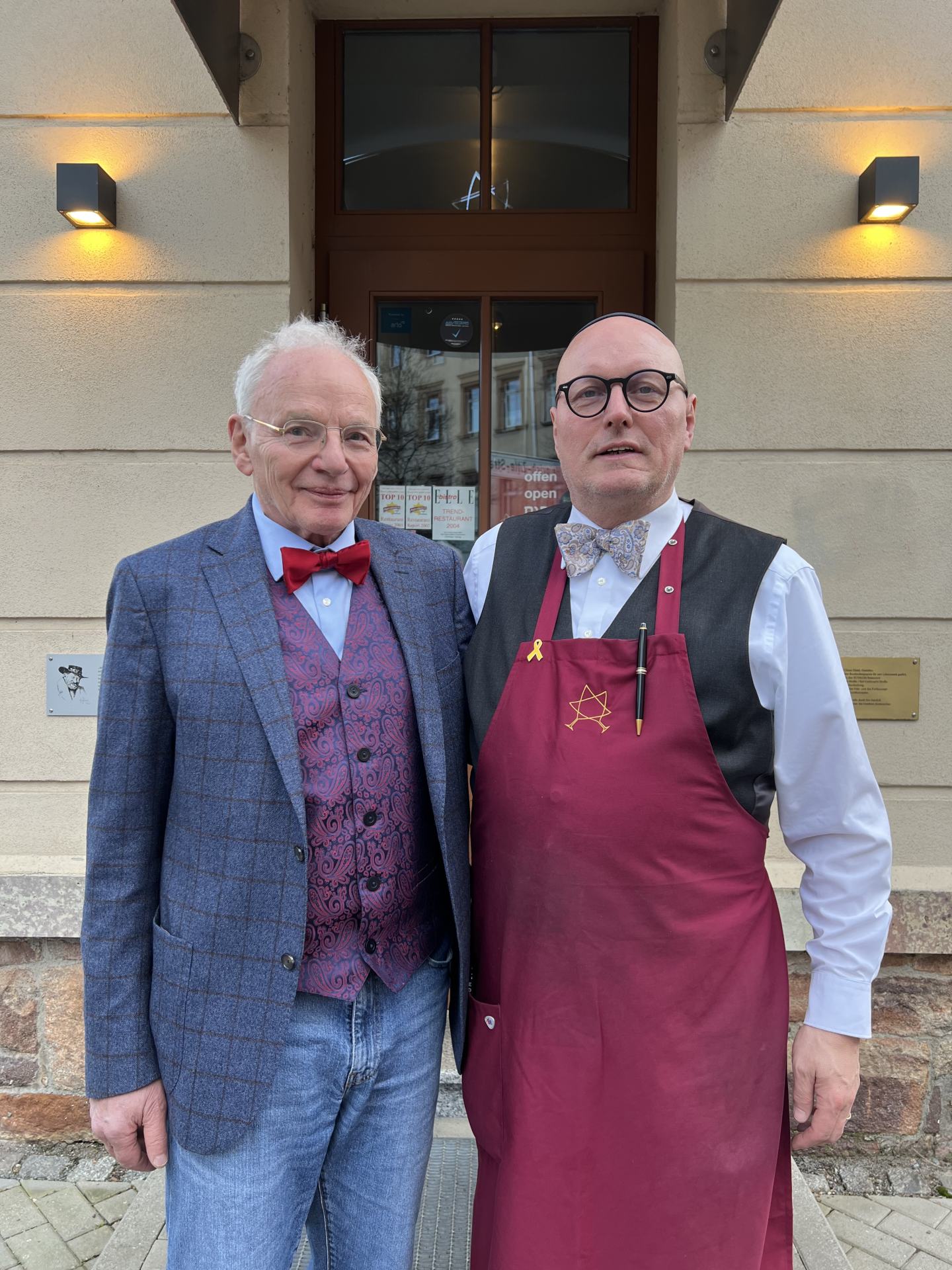 Zwei ältere Herren stehen vor einem Gebäude. Der linke Herr ist der Autor Götz Aly und der rechte Herr ist der Besitzer des Restaurants SCHALOM, Uwe Dziuballa