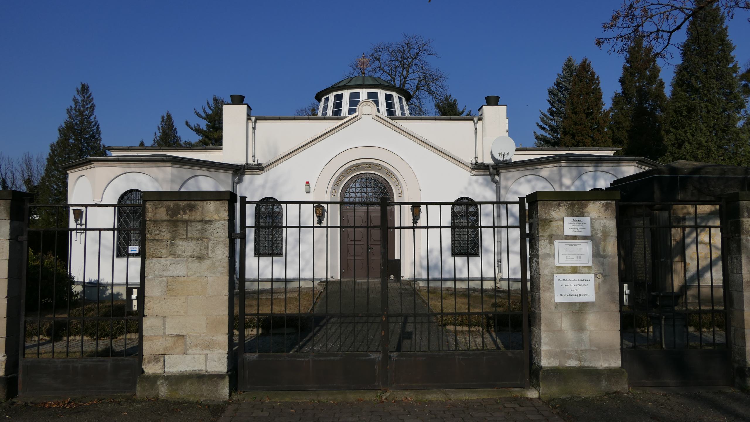 Der Eingang des neuen jüdischen Friedhofs. Dahinter sieht man die weiße Trauerhalle.